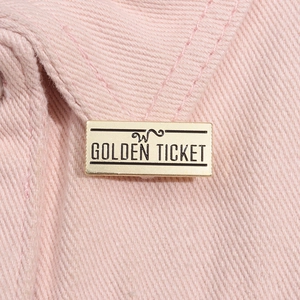 Vue macro détaillée d'un badge métallique doré ticket sur un tissu en sergé rose clair