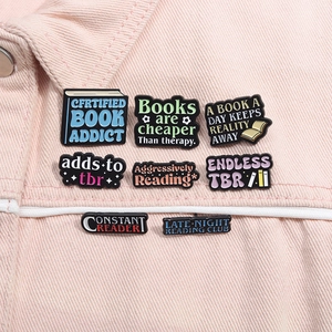 Enamel bookworm pins with motivational quotes pinned on a pink denim jacket detail