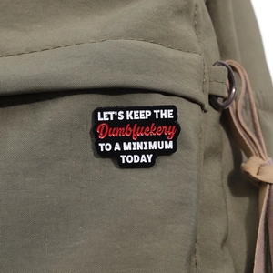 Nahaufnahme einer lustigen Emaille-Anstecknadel an einem grünen Canvas-Taschenriemen