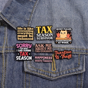 Enamel accounting lapel pins set on denim jacket featuring fun tax season humor