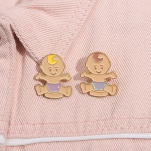 Close-up of cute twin baby enamel pins with glitter details on pink denim fabric