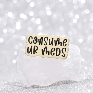 Creative enamel brooch with Consume Ur Meds text on gold-tone irregular wavy metal frame