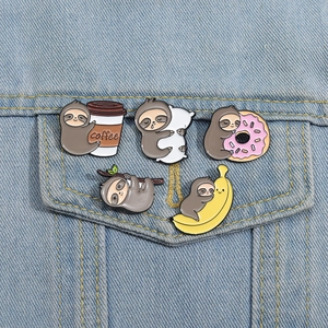 Detailed view of cute cartoon sloth enamel pins styled on a denim jacket pocket