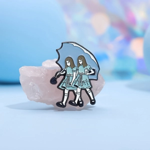 Dunkle Punk-Emaille-Anstecknadel mit Zwillingsmädchen unter blauem Schirm auf Kristall