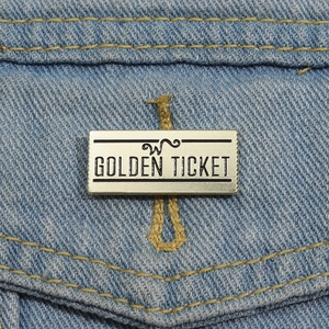 Macro de la broche rectangulaire Golden Ticket en métal fixée sur une veste en jean bleue
