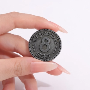 Dettaglio macro di una spilla vintage in metallo con il numero 8 e testo inciso