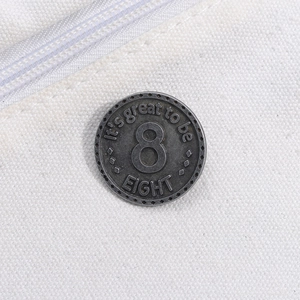 Dettaglio di un distintivo vintage in metallo argento numero 8 su tela bianca