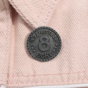 Dettaglio del distintivo in argento vintage con numero 8 su tessuto rosa