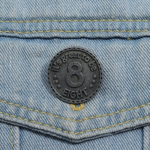 Dettaglio macro di un bottone in metallo vintage con numero 8 su denim blu chiaro