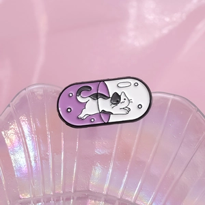Cute capsule-shaped enamel pin featuring a cartoon cat design on pink silk background