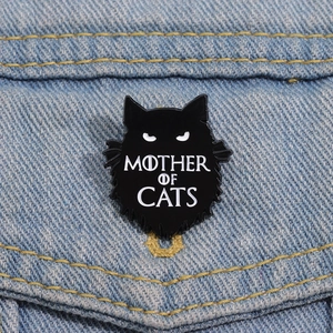 Détail d'un pin's chat noir en émail avec texte Mother of Cats sur tissu en denim