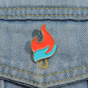 Detailansicht der flammenden Emaille-Anstecknadel an einer hellblauen Jeansjacke