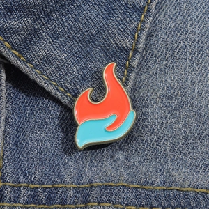 Cartoon-Flammen-Emaille-Anstecknadel in Rot und Blau auf dunkelblauem Denim-Stoff