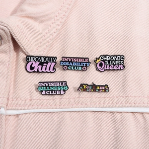 Gros plan de cinq épingles en émail colorées avec des phrases positives sur une veste