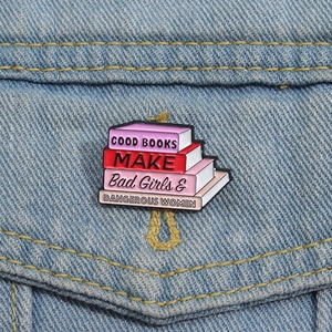 Gros plan d'une broche livre en émail rose épinglée sur un tissu en jean bleu