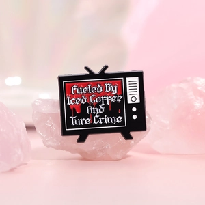 Retro TV enamel pin featuring 'Fueled By Iced Coffee And True Crime' text on pink crystal