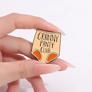 Broche créative en émail avec texte Granny Panty Club sur un fond rose poudré
