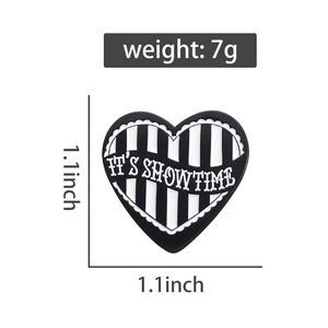Detail view showing a black and white striped heart enamel pin with IT'S SHOWTIME text