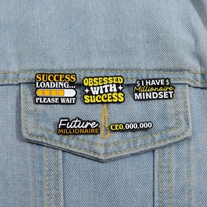 Dettaglio di spille smaltate motivazionali su giacca di jeans con frasi sul successo