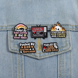 Detailed view of five enamel coffee badges pinned on a light blue denim jacket pocket