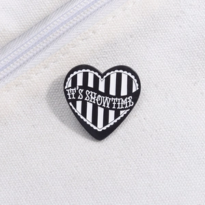 Macro shot of striped heart enamel pin with IT'S SHOWTIME text on white canvas bag