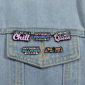 Détails de cinq pin's en émail colorés avec des citations motivantes sur une veste