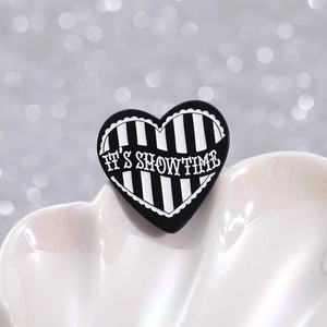 Minimalist heart enamel brooch with black white stripes and It's Showtime text in shell tray