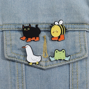Dettaglio di quattro spille smaltate con animali colorati su una giacca di jeans blu