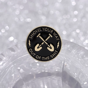 Enamel badge with shovel cross and text Shovel Your Way Out Of The Shit on crystal edge