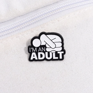 Gros plan du pin's en émail I'M AN ADULT sur toile blanche pour veste en jean