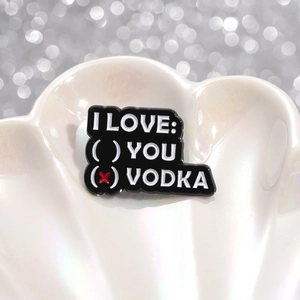 Funny black enamel pin badge with I Love Vodka text design on a white shell background