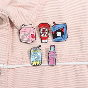 Détail de cinq pin's créatifs en émail représentant des bouteilles de soda sur denim rose