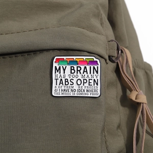 Close-up of colorful folder enamel pin on green canvas backpack with humor quote