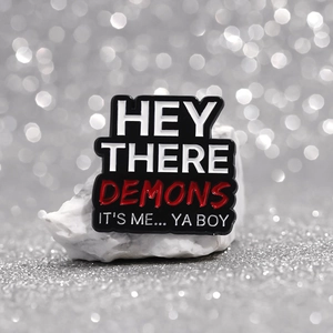Creative enamel pin with 'Hey There Demons' text on white stone with bokeh background