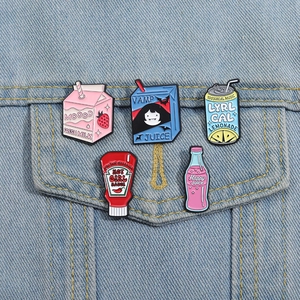 Close-up of five colorful enamel pins styled as sodas and sauces on a denim jacket