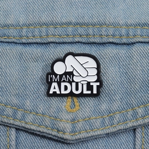 Détail du pin's émaillé I'M AN ADULT épinglé sur la poche d'une veste en jean