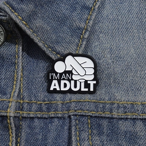Détail macro du badge émaillé 'I'M AN ADULT' fixé sur le col d'une veste en jean bleu