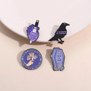 Gothic purple enamel pins set with heart, raven, coffin shapes and dark floral patterns