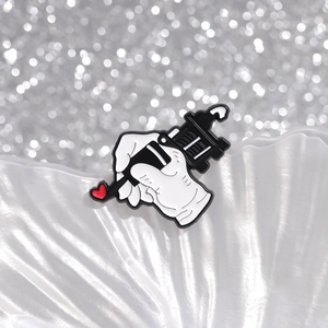 Creatieve emaille broche met tatoeagemachine en rood hartje op decoratieve basis