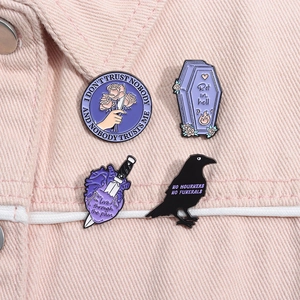 Set of four gothic enamel pins on pink denim, featuring raven, coffin, and heart designs