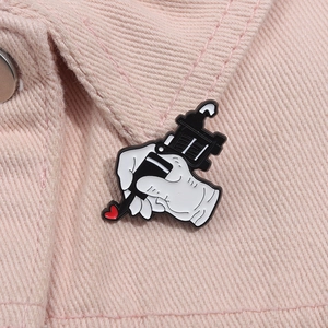 Detail van een geëmailleerde pin met tatoeagemachine op roze denim stof