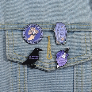 Set of gothic enamel pins with purple coffin and black raven on denim jacket