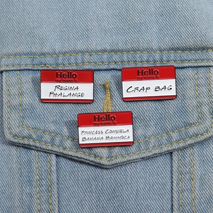 Close-up of three enamel pins on a denim jacket featuring iconic TV show name tag quotes