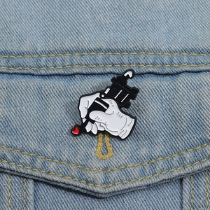 Detail van cartoon tatoeagemachine emaille speld met hart op denim stof
