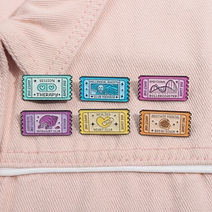 Set of six colorful enamel ticket pins with mental health themes on pink corduroy fabric