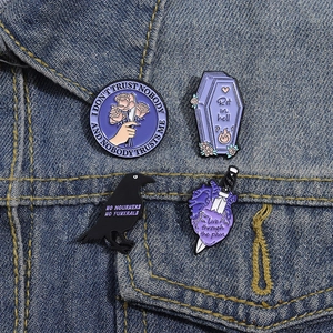 Gothic purple enamel pin set with raven and coffin designs on a denim jacket