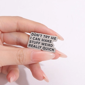 Macro shot of silver metal brooch with black motivational text and wavy edges