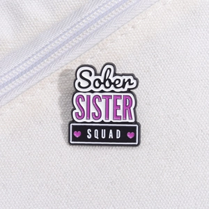 Macro shot of Sober Sister Squad enamel pin on white canvas bag with zipper detail