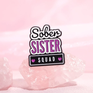 Sober Sister Squad enamel pin with purple hearts on a decorative pink crystal stone