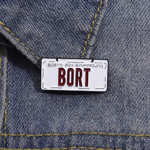 Detail shot of the BORT license plate enamel pin on a blue denim jacket texture